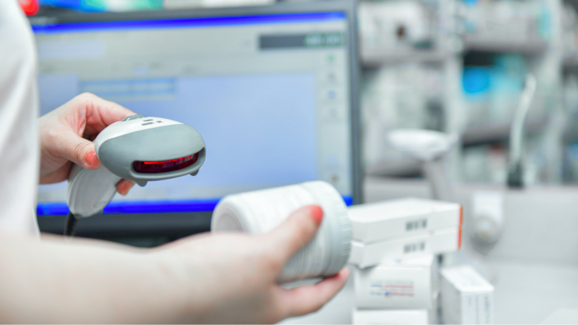 Pharmacist using a barcode scanner for scan-to-shelf inventory management in a UK pharmacy.
