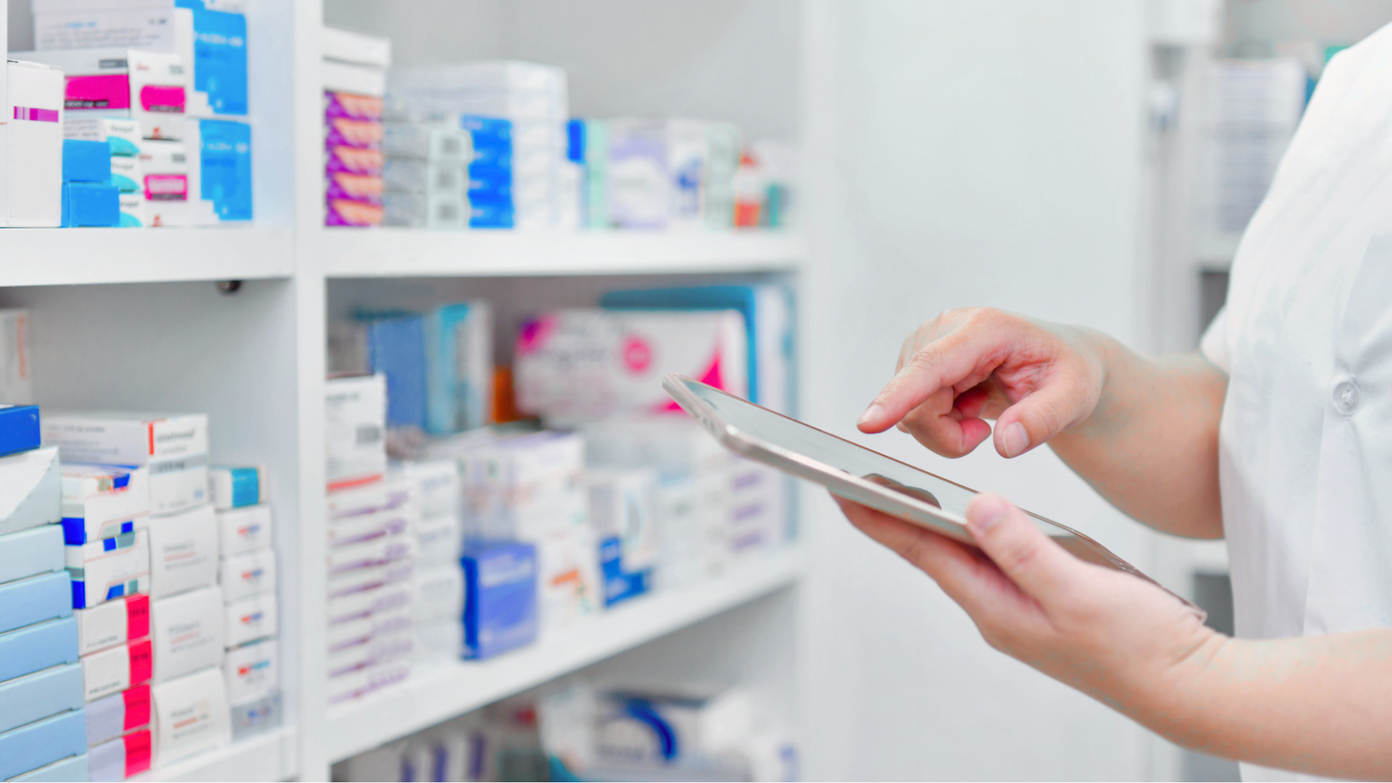 Pharmacist using a tablet to monitor inventory levels and prevent medication stockouts.